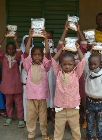 Children carrying bags of rice home from a distribution day